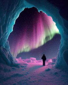 a person standing in front of an ice cave with the aurora bore visible above it