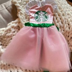 there is a pink and green dress on top of a white blanket with a starbucks logo