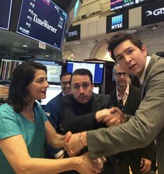 two men shaking hands in front of people at an stock market