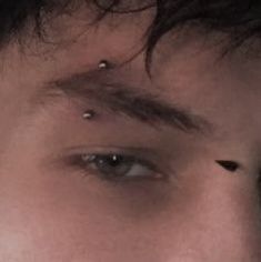 a man with piercings on his nose looking at the camera