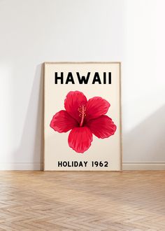 a red flower sitting on top of a wooden floor in front of a white wall