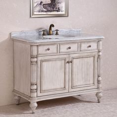 a white bathroom vanity with marble top and two faucets on the sink area