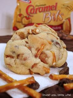 a chocolate chip cookie and some pretzels on a white towel next to a bag of caramel bits