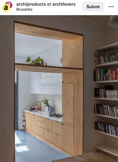 an open kitchen and living room area with bookshelves on the wall in front of them