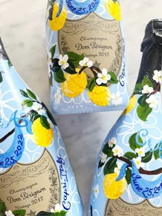 three blue and yellow painted bottles with flowers on them sitting on a marble counter top