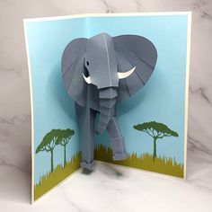 an elephant made out of paper sitting on top of a white marble table next to a blue wall