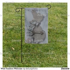 a garden flag with an image of a teddy bear on it in the middle of grass