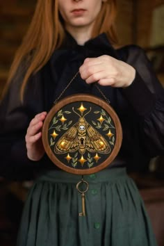 a woman holding up a clock with an insect on it