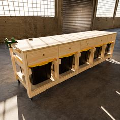 a large wooden table with four black bins on it's sides in an empty room