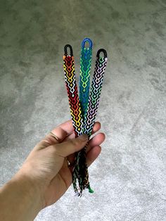 a hand holding three different colored lanyards in it's left hand on the floor