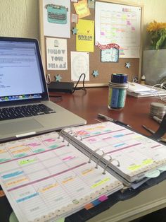 a laptop computer sitting on top of a wooden desk next to a pile of papers