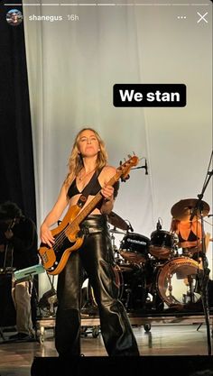 a woman standing on top of a stage with a guitar in her hand and another person behind her