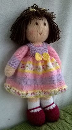 a knitted doll wearing a pink and yellow dress