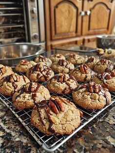 cookies with pecans and chocolate drizzled on them sitting on a cooling rack