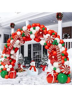 an arch decorated with christmas balloons and candy canes in front of a white house