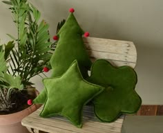 three green pillows sitting on top of a wooden bench next to a potted plant