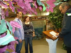 two men and a woman looking at something on a table