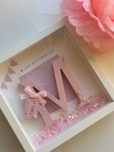 a pink and white greeting card with the letter v in it's box next to a flower