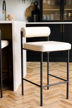 a white counter top sitting next to a bar stool in a room with wooden floors