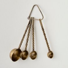 three metal spoons hanging from a hook on a wall