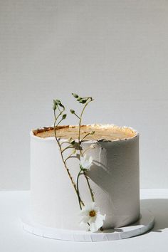 a white vase with flowers in it sitting on a table