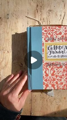 a person holding a book in their hand on top of a wooden table with the title garden journal written above it