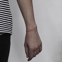 a person with a small tattoo on their arm holding the hand of another person wearing a black and white striped shirt