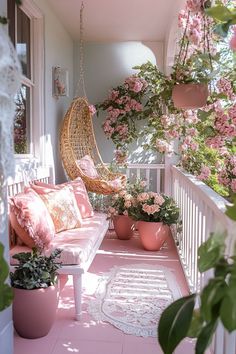 the porch is decorated with pink flowers and hanging planters, along with wicker hammock