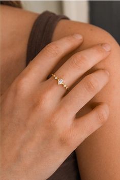 a woman's hand wearing a gold ring with three diamonds on the middle finger