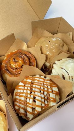 an open box filled with donuts covered in frosting and caramel toppings