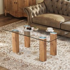 a glass coffee table sitting on top of a rug in front of a brown couch