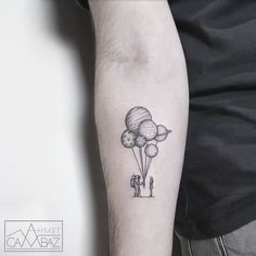 a man with a tattoo on his arm holding onto some balloons that are floating in the air