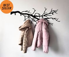 two coats are hanging on the wall next to a tree branch and an orange circle