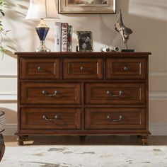 a wooden dresser with many drawers and pictures on it's top shelf in a living room