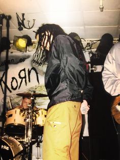 two men with dreadlocks are playing guitars and singing into microphones while another man stands behind them