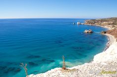 the water is crystal blue and clear with rocks on either side, and cliffs in the distance