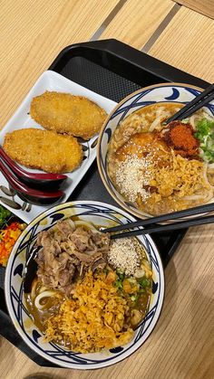 three plates of food on a tray with chopsticks