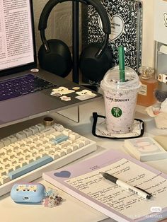 a desk with a laptop, keyboard and headphones on it next to a cup of coffee