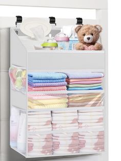 an organized closet with baby diapers, blankets and a teddy bear sitting on the top shelf