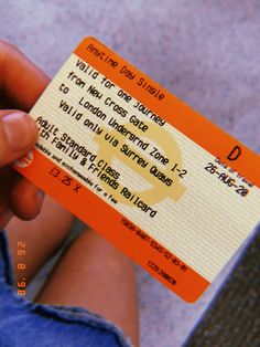 a person holding up a yellow and orange ticket with the letter d on it's side