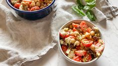 two bowls filled with food sitting on top of a white table next to each other