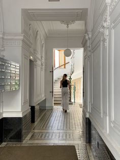 a woman is walking down the hall with her back to the camera