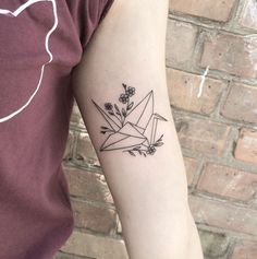 a person with a tattoo on their arm that has an origami bird and flowers