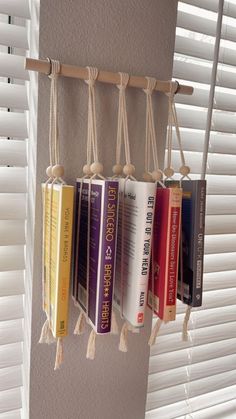 some books are hanging from a rack with tassels attached to the book ends