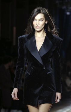 a model walks down the runway in a black suit