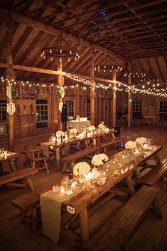 a long table with candles on it in a barn