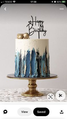 a white and blue birthday cake on a gold plate with the words happy birthday written on it