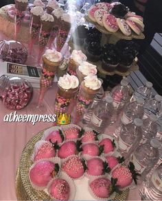 a table topped with lots of cupcakes covered in pink frosting