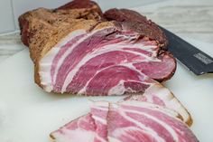 sliced meat on a cutting board next to a knife