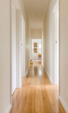 an empty hallway with hard wood floors and white walls